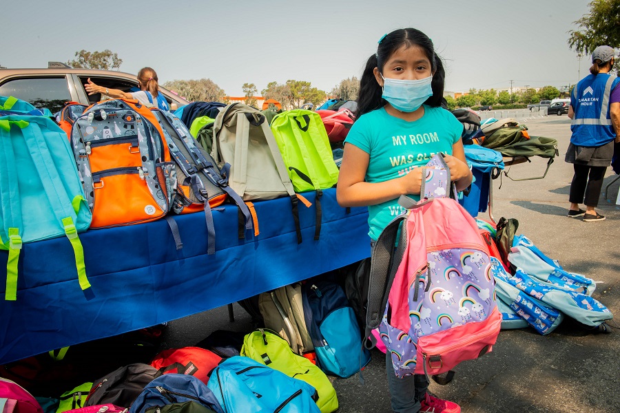 Girl holding a pink and purple rainbow backpack